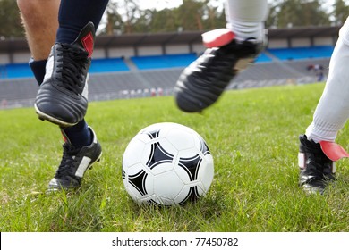 Horizontal image of soccer ball on the field with footballers legs near by