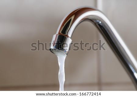 Horizontal image of a tap with water flowing slowly during a period of scarcity