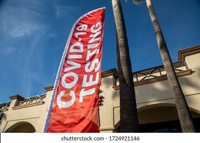 Horizontal image of vertical red flag sign with white capital letters stating COVID-19 TESTING in shopping mall
