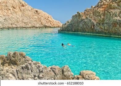 Horizontal Image Of Young Caucasian Couple Swimming In Turquoise Crystal Clear Waters Of Seitan Limania Secluded Beach On Sunny Summer Day, Crete, Greece