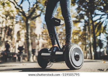 Horizontal image of young hipster girl riding on electric segway at sunny park, active woman using modern alternative transport hoverboard outdoor, ecology and environment concept
