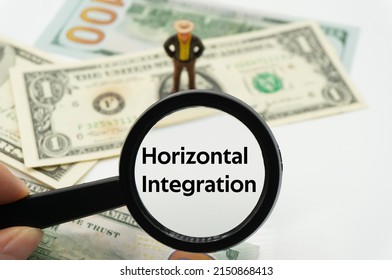 Horizontal Integration.Magnifying glass showing the words.Background of banknotes and coins.basic concepts of finance.Business theme.Financial terms.