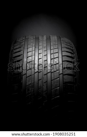 Horizontal isolated in darkness TYRE and tyre pattern, auto equipment having the top surface lighted on black background  