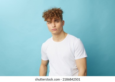 horizontal isolated portrait of a handsome man with curly hair smiling pleasantly at the camera while standing in a casual white T-shirt - Powered by Shutterstock