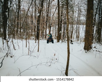 A Horizontal, Landscape Frame Of A Four Wheeler Quad Riding Through The Snow Covered Country Woods After A Severe Winter Storm. A Partly Cloudy Sky Shines On The Covered Trees, Farm, And Mountains.