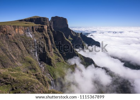 A horizontal landscape photograph of the Tugela Falls falling over the escarpment edge in the uKhahlamba Drakensberg Park in South Africa. A cloud iversion sits below and blue sky overhead. Stock photo © 