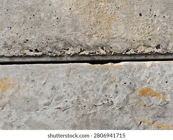 A horizontal line gap between two weathered precast concrete panels with rustic stains, close up.