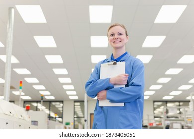 Horizontal Low Angle Portrait Of A Smiling Female Engineer Holding A Clipboard In A Hi-tech Electronics Factory.