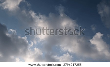 Horizontal low-angle shot of a dramatic blue sky filled with fluffy cumulus clouds, highlighting the beautiful contrast between bright white sunlit edges and soft gray shadows in the morning.