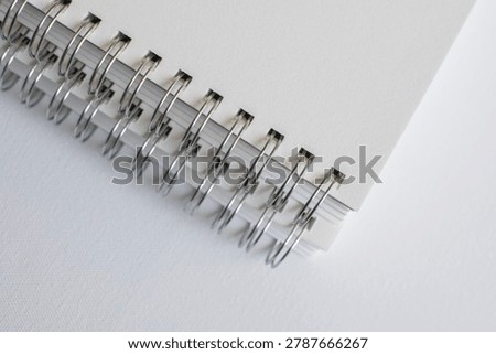 Horizontal macro close up of spiral notebook binding on white surface in studio. Minimal stationery, modern publishing, elegant branding, creative workspace, clean texture.