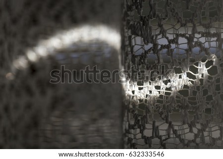 Horizontal macro view of curvy light patterns of sunlight that spills into the old net curtains hanging from the windows at grandma's house. Town of Malmsheim near Stuttgart, Gremany.