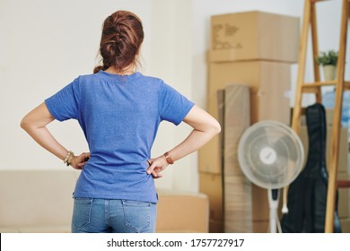 Horizontal Medium Back View Shot Of Unrecognizable Woman Standing With Hands On Hips Looking At Things To Sort Out