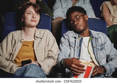 Horizontal medium portrait of young Black man having nap while his Caucasian girlfriend watching movie at cinema - Powered by Shutterstock