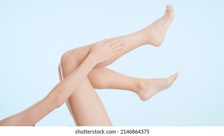Horizontal medium shot of female legs. Young slim lying woman touches her leg on pale blue background | Leg care and unwanted hair removal concept - Shutterstock ID 2146864375