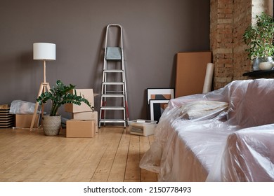 Horizontal No People Shot Of Spacious Loft Living Room Interior In Modern Apartment With Boxes Unpacked, Ladder, Sofa And Various Things