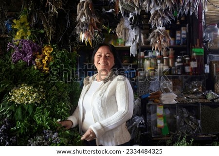Horizontal open portrait of a smiling Latina young woman looking at camera. Background of medicinal herbs and flowers. Taken in Merida, Venezuela. Concept of peoples and traditions. real people.