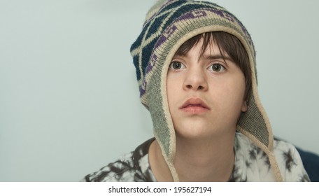 Horizontal Orientation Close Up Of A Boy With Autism And Down's Syndrome Wearing A Wool Winter Hat With A Neutral Background And Copy Space / Winter Hat On A Teenager With Autism And Down's Syndrome