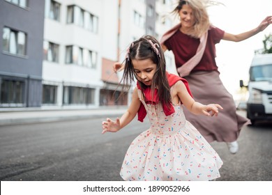 Horizontal Outdoor Image Of A Happy Little Girl Playing Hopscotch With Her Mother On Playground Outdoors. Child Plays With Her Mom Oustside. Kid Plays Hopscotch Drawn On Pavement. Activities And Games