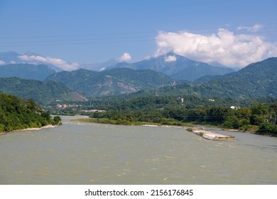 Horizontal panoramic shot of the clouds above the mountains, river rapids, green forest at the Dujiangyan Irrigation System, Dujiangyan, Sichuan, China 