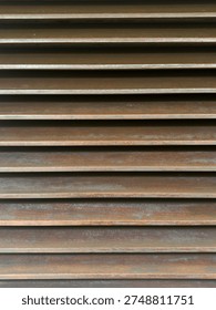 Horizontal parallel slats with a rustic, weathered brown metallic finish, creating a rhythmic shadow pattern.