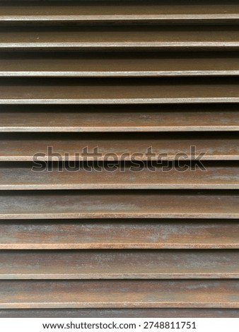Horizontal parallel slats with a rustic, weathered brown metallic finish, creating a rhythmic shadow pattern.