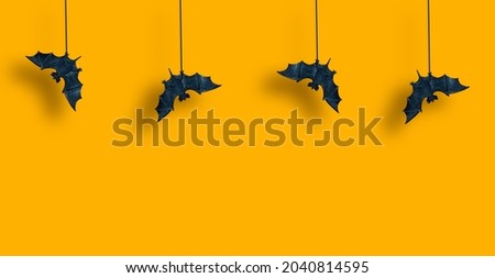 Horizontal pattern. Black bats in row are suspended with spread wings on yellow orange background. Hallowen. Copy space