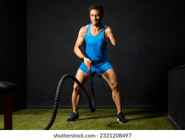 Horizontal photo of an adult athlete with an amputated arm performing a battle rope exercise inside a gym. Battle rope concept, disabled bodybuilders, athletes with an amputated arm.Improvement. - Powered by Shutterstock