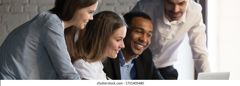 Horizontal photo banner for website header design, diverse employees gathered in office having fun watching funny video, discussing new ideas, brainstorming using laptop enjoy break in workday concept - Powered by Shutterstock