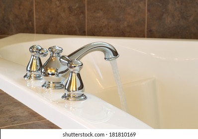 Horizontal Photo Of Chrome Faucet Running Water Into Soaking Tub In Master Bathroom 