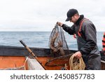 Horizontal photo with copy space of a fisherman holding a net with lobsters on a boat