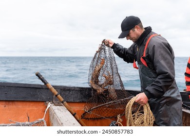 Horizontal photo with copy space of a fisherman holding a net with lobsters on a boat - Powered by Shutterstock