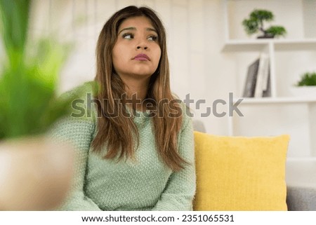 Horizontal photo with copy space and selective focus of a thoughtful and anxious woman sitting on the sofa