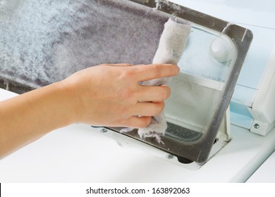 Horizontal photo of female hand taking the lint out from dirty air filter of the dyer machine 