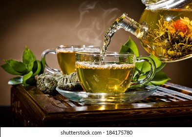 horizontal photo, of the glass teapot flow green tea in cup on brown background,  tea ceremony
