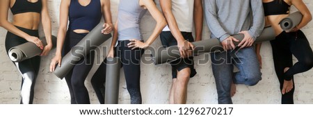 Horizontal photo group young sporty people wearing activewear holding yoga mats standing near wall before or after training, healthcare and active lifestyle concept, banner for website header design