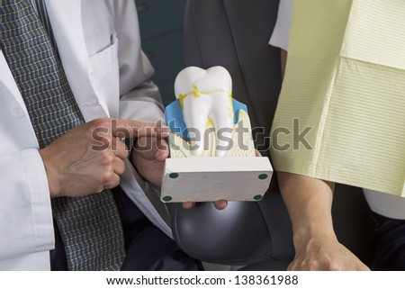 Horizontal photo of a male dentist educating female patient on teeth care with model teeth display