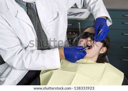 Horizontal photo of a male dentist examining young girls teeth