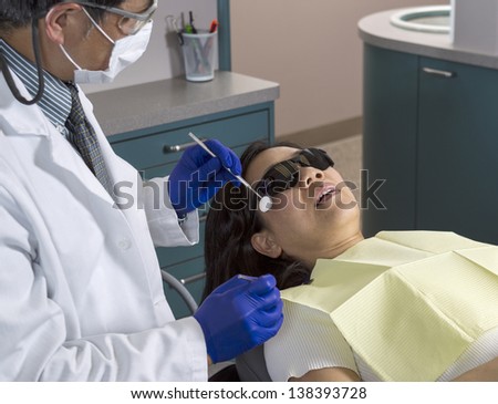 Horizontal photo of a male dentist preparing to work on woman patient