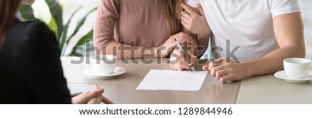 Horizontal photo married couple and realtor sitting at desk in office, wife and husband renting property buying first new home house signing rental agreement contract, banner for website header design Stockfoto © 