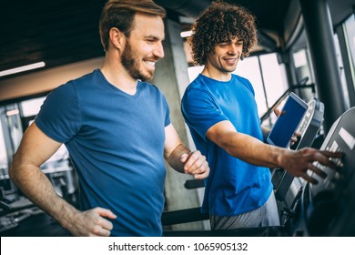 Horizontal Photo Of Middle Aged Man Jogging On Treadmill At Health Club. Training With Fitness Instructor.