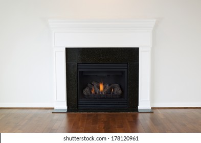 Horizontal photo of a natural gas fireplace with a white mantle and cherry wood floors 