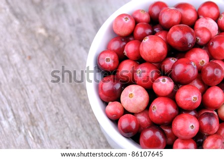 Horizontal photo of organic, wild cranberries in white ramekin on rustic wooden background