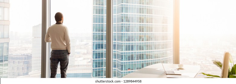 Horizontal photo rear back successful businessman look through window at big city, rest has break, think about future business vision concept, banner for website header design with copy space for text