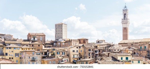 Horizontal photo with view on the town hall tower over the houses and buildings in historic ancient town Siena in Italy Tuscany. The sky is blue with several clouds.  - Powered by Shutterstock