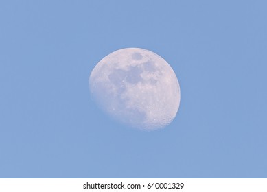 Horizontal photo of white big moon. Moon is captured during a day time with clear blue sky and few days before full-moon so only small part is hidden in shadow of Earth.