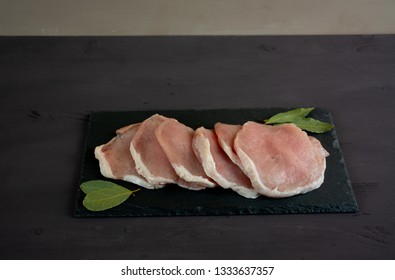 Horizontal Photo Of Whole Pork Tenderloin Raw Meat Is On A Black Slate Dish With Aromatic Herbs