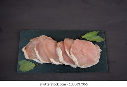 Horizontal Photo Of Whole Pork Tenderloin Raw Meat Is On A Black Slate Dish With Aromatic Herbs