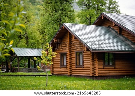 Horizontal photo of  wooden house in  green forest. Pros and cons of  wooden house and suburban real estate concept.