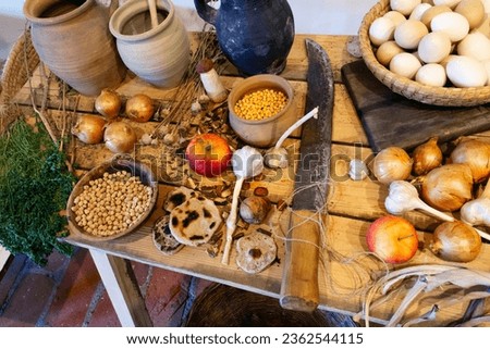 A horizontal photo of a wooden table with vegetables and various things spread out on it