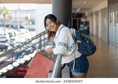 Horizontal photograph of a beauty brown skin woman traveling alone in her 20s, enjoying her vacation with a smile, going shopping in stores in Mexico with her backpack